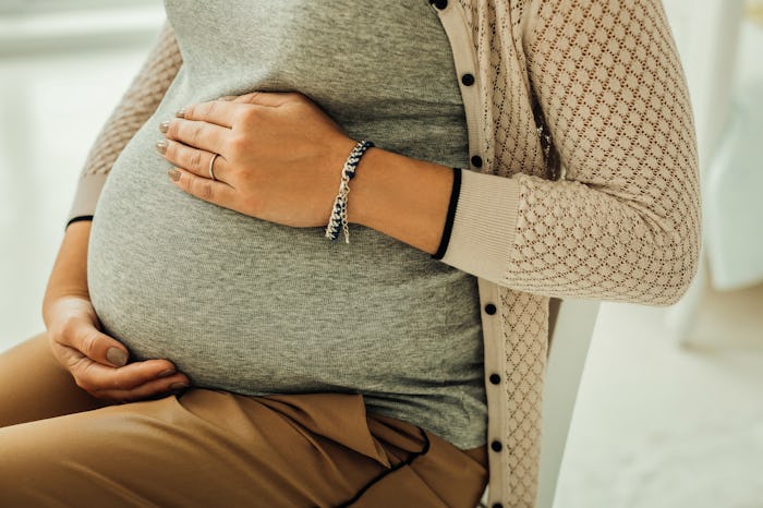 Pregnant belly. A woman touching her third-trimester pregnant belly