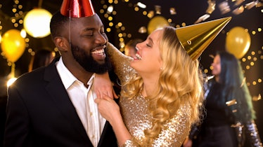 Glad mixed-race couple in party hats celebrating birthday, holiday entertainment