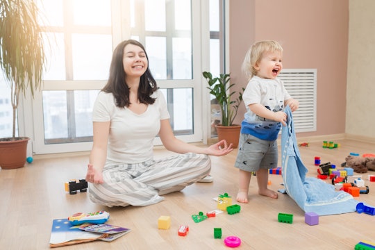 Portrait of young happy yoga mom spending time with her little baby boy, meditating in lotus positio...