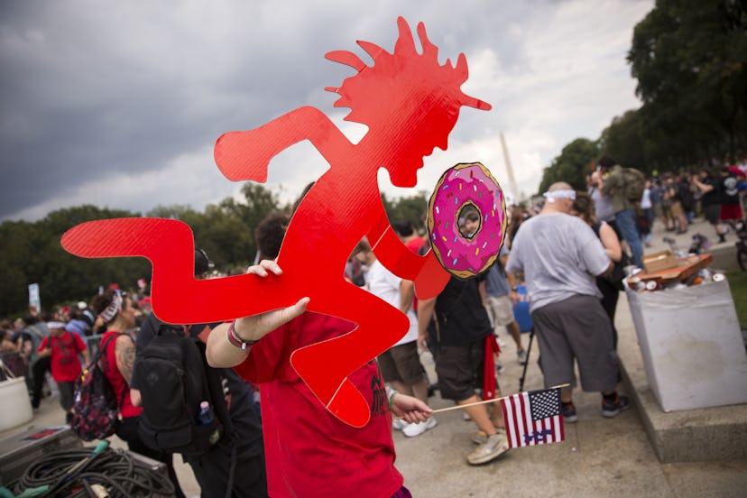 A Juggalo, fan of the band Insane Clown Posse, carries a Hatchetman with a doughnut during the Jugga...