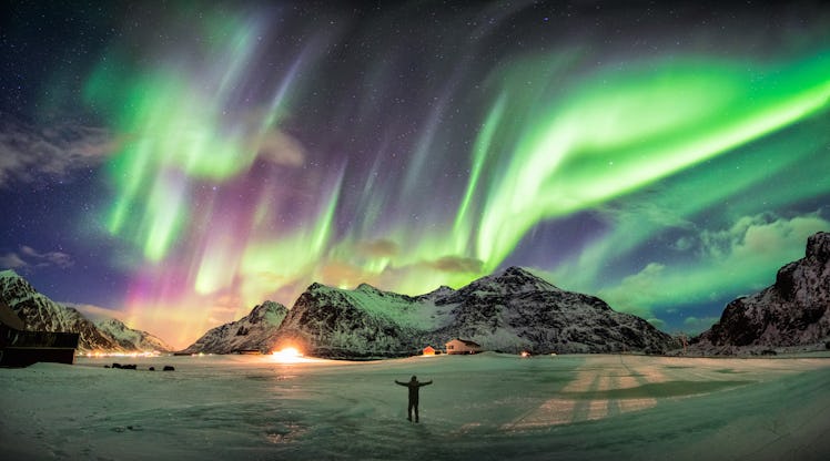 Aurora borealis (Northern lights) over mountain with one person at Skagsanden beach, Lofoten islands...