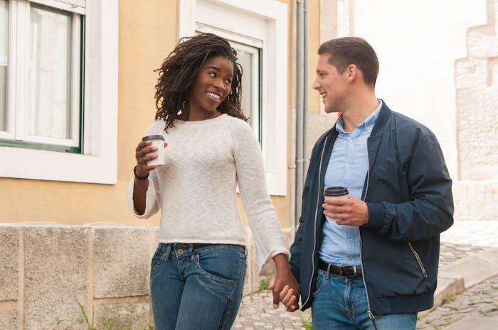 Happy cheerful interracial couple enjoying date. Afro American girl and her Caucasian boyfriend hold...
