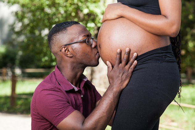 african american man kissing the belly of his pregnant wife