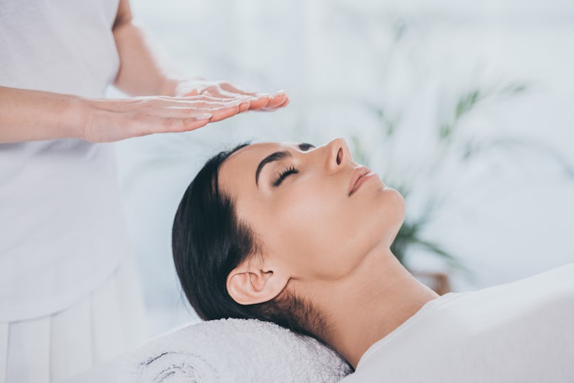 close-up view of peaceful young woman with closed eyes receiving reiki treatment
