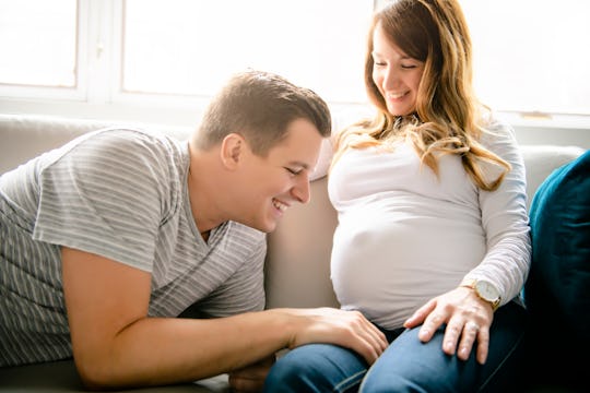 A happy man with pregnant woman sitting on couch