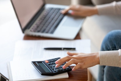 Businesswoman using calculator and laptop for budget cost money management strategy, female hands ca...