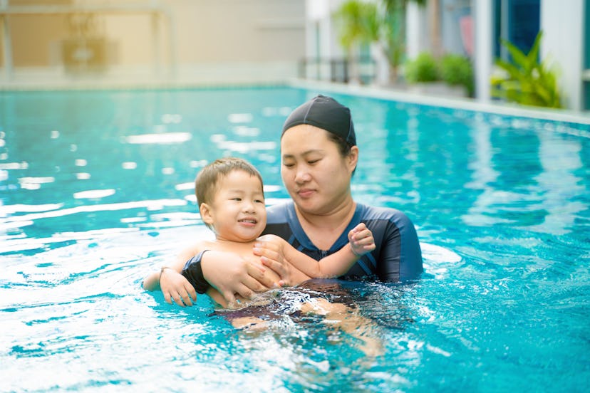 Child boy learn swimming with mom in swimming pool outdoor relax