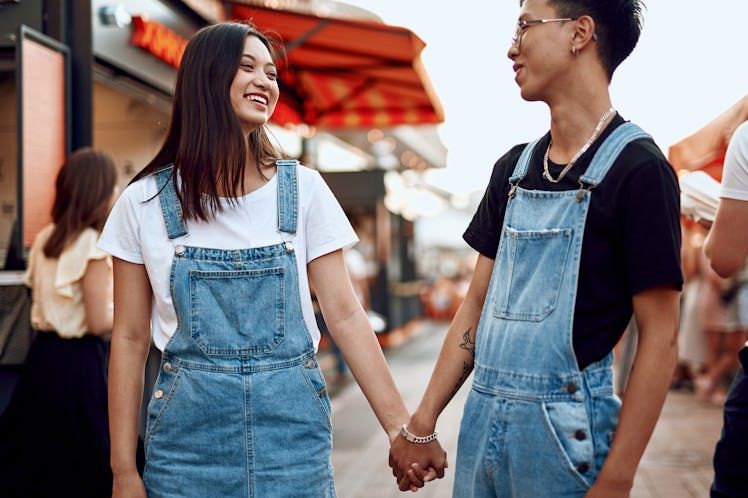 Love and date concept. Young happy asian man and woman walking together around city holding hands