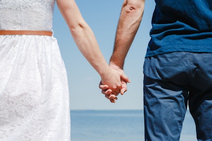 Close up of loving couple holding hands on a beach near the sea