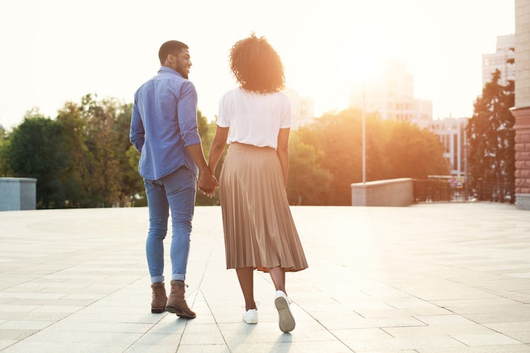 Couple holding hands and walking in the city at sunset