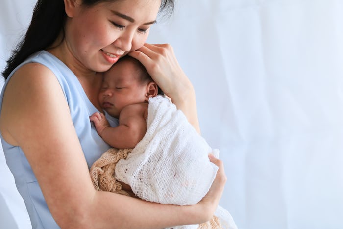 Selective focus Asian beautiful mother hold newborn baby 0-1 month in her arm with love and gently, ...
