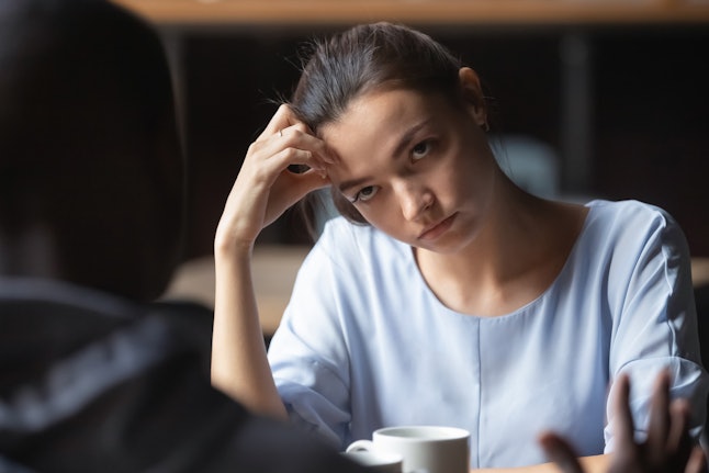 Bored unhappy girlfriend listening to African American boyfriend in cafe, bad first impression and date concept, multiracial couple having sitting at table, talking, having problem in relationships