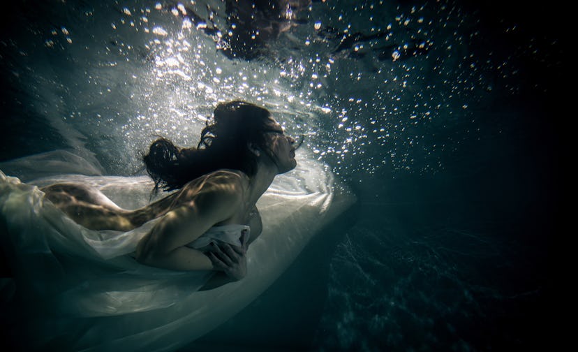 Beautiful woman swimming underwater with elegant dress