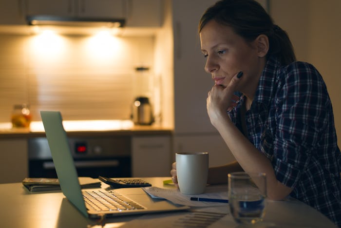 Serious woman thinking while reading an e-mail on laptop at home