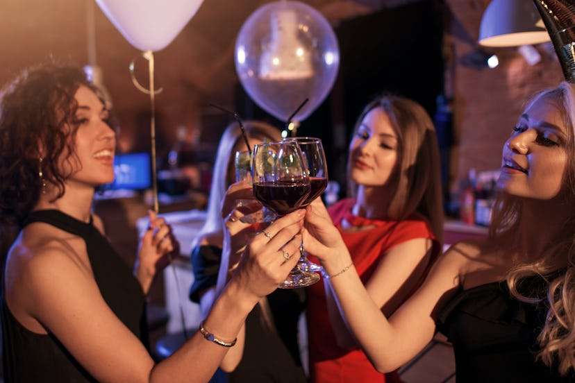 Group of cheerful girls having a party standing clinking glasses together at night club