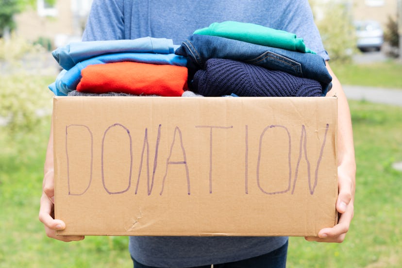 Man holding a Donate Box with clothes, donation and charity concept