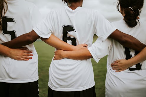 Female soccer players huddling and standing together