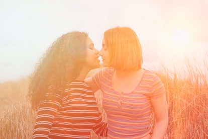 Lesbian couple in love kissing in romantic scenery of sunset on the beach in summer - Image