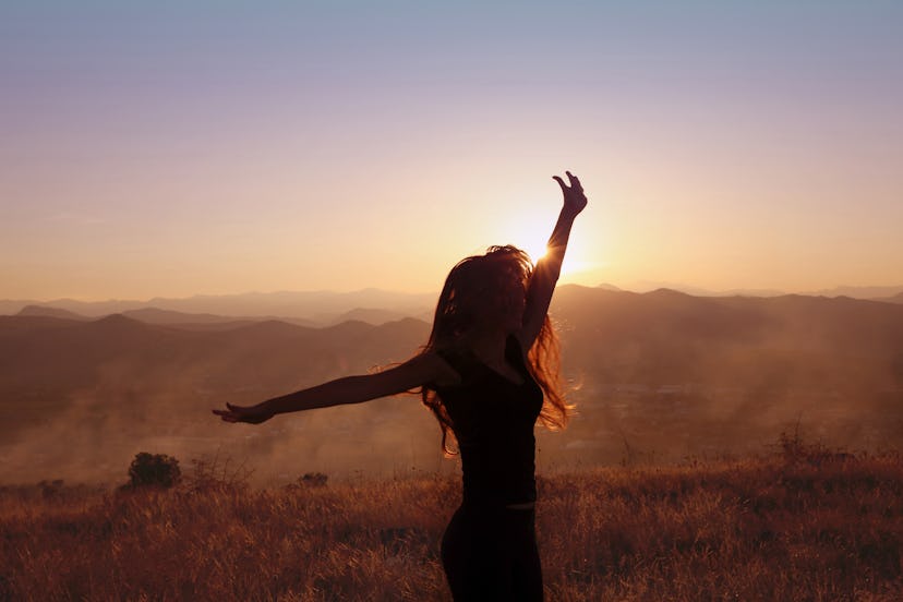 Sunset mountain. Free woman outstretched arms with blowing hair running in wheat field enjoying life...