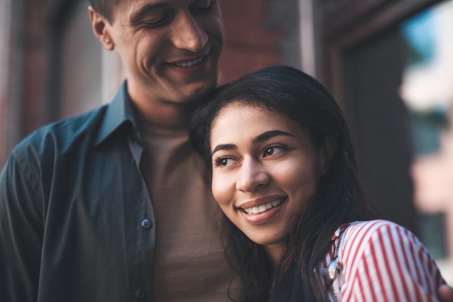 Cheerful couple. Kind calm man kindly looking at his happy girlfriend and seeing her smiling happily while leaning to him