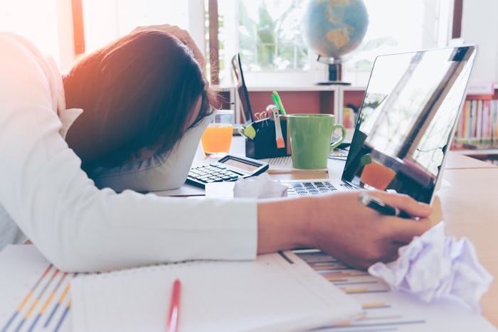 Overworked and tired young woman sleeping on desk