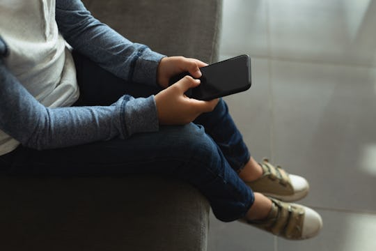 Low section of mixed race boy using mobile phone in the lobby at hospital