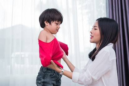 Young Asian mom dressed up son shirt for preparing go to school. Mother and son concept. Happy famil...