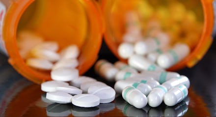 Medication overuse or adverse drug interaction concept - two types of prescription drugs spilling fr...
