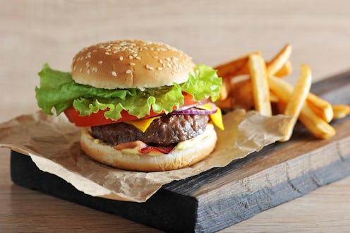Cheeseburger from chopped beef cutlet with tomato, salad, bacon, sauce and red onion. Next to the ch...