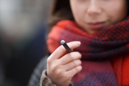 Young vaper girl hold new vape pen stick cigarette in hand.Vaping girl holds e-cig device in hand.Sm...