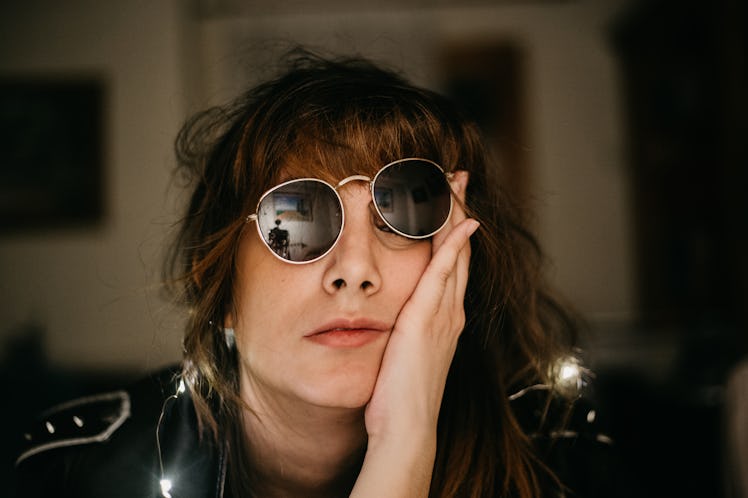 portrait of bored young woman with led lights sunglasses and hand in the face