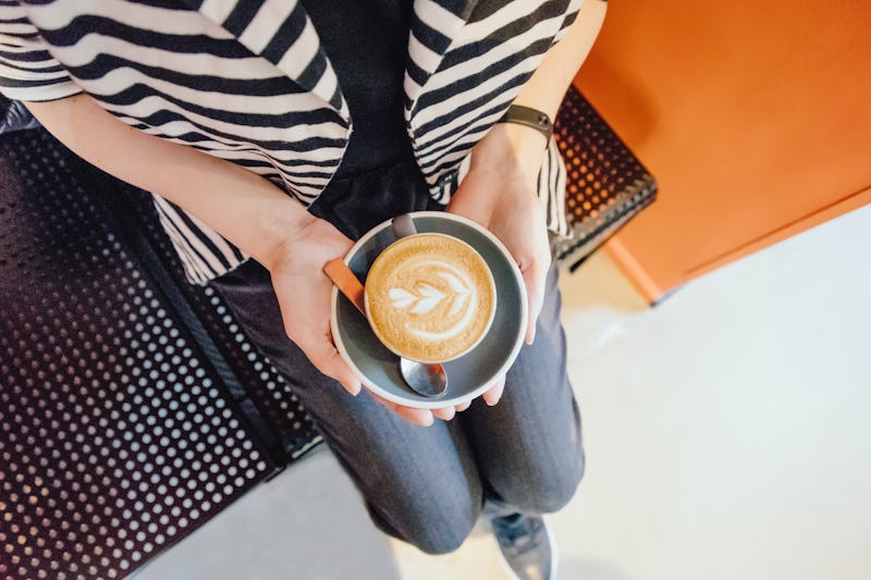 Female hands with a coffee cappuccino cup. Top view, copy space. Toned photo