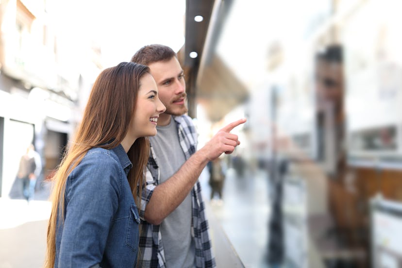 Happy couple checking storefront talking about products in the street