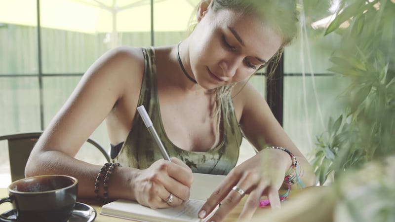 Woman writing in journal in cafe, working in mobile office