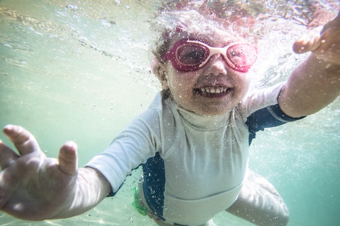 Happy child toddler swimming underwater during summer beach holidays vacation