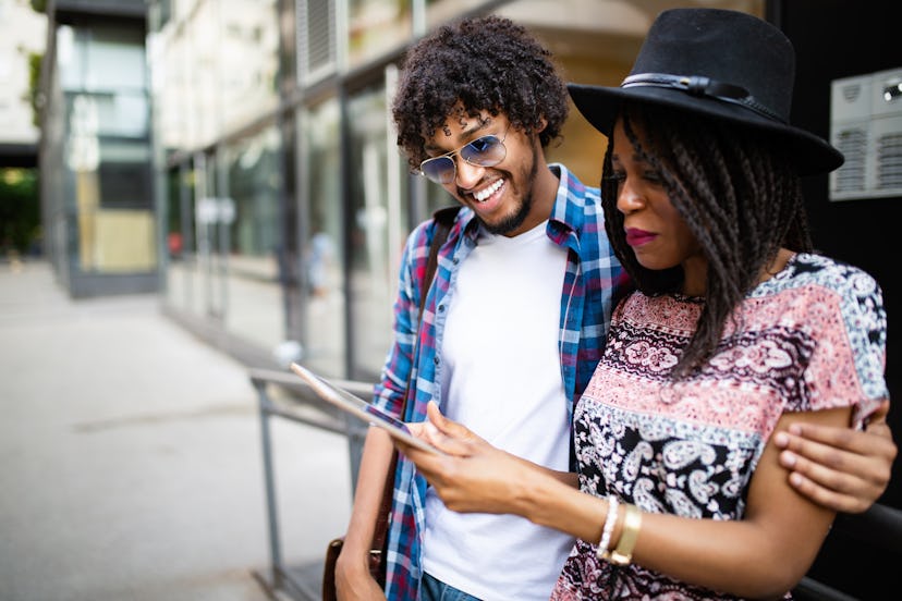 Young attractive african couple talking and looking at digital tablet.