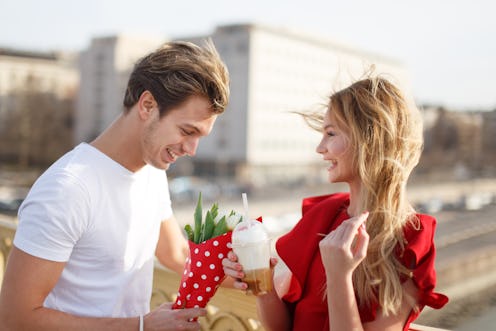 Young man give bouquet to woman in red dress at first date