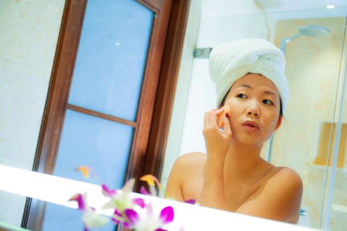 lifestyle fresh portrait of young happy and beautiful Asian Korean woman at home or hotel bathroom w...