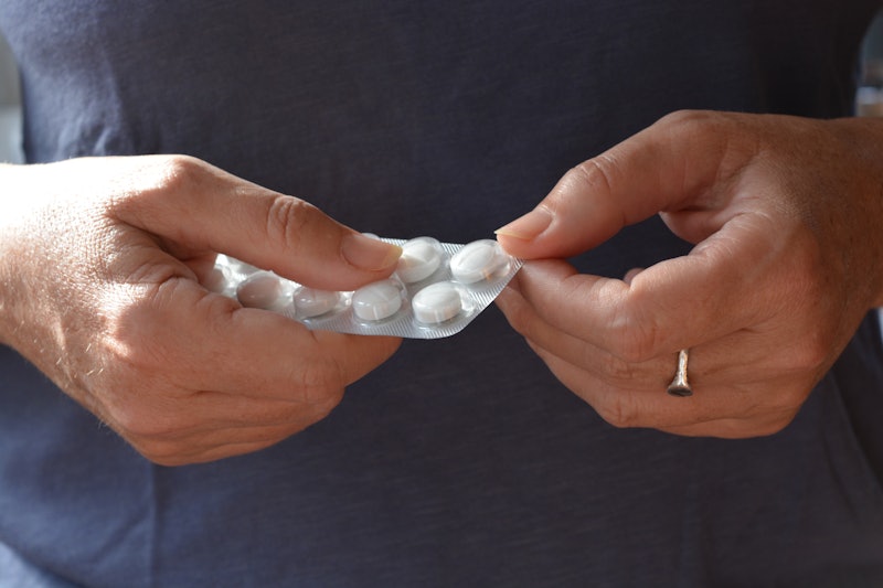 woman taking a pill from a blister pack of generic white tablets