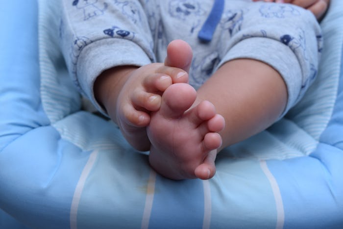 Small baby's feet sitting in a blue baby bouncer