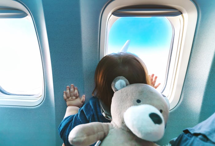 Little toddler boy looking out an airplane window while flying