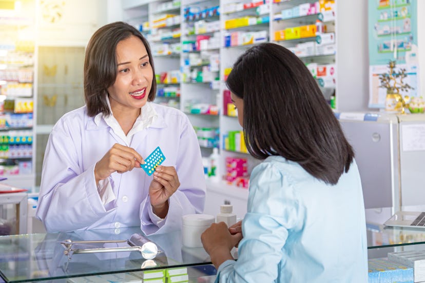 Female pharmacist counseling customer about contraceptive pill usage in modern pharmacy. Medicine, p...