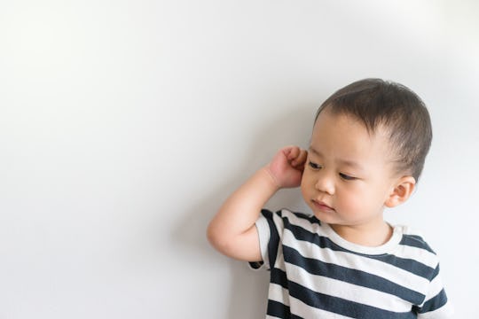 Little baby boy has earache and tugs at his ear, in a story about how to prevent ear infections in k...