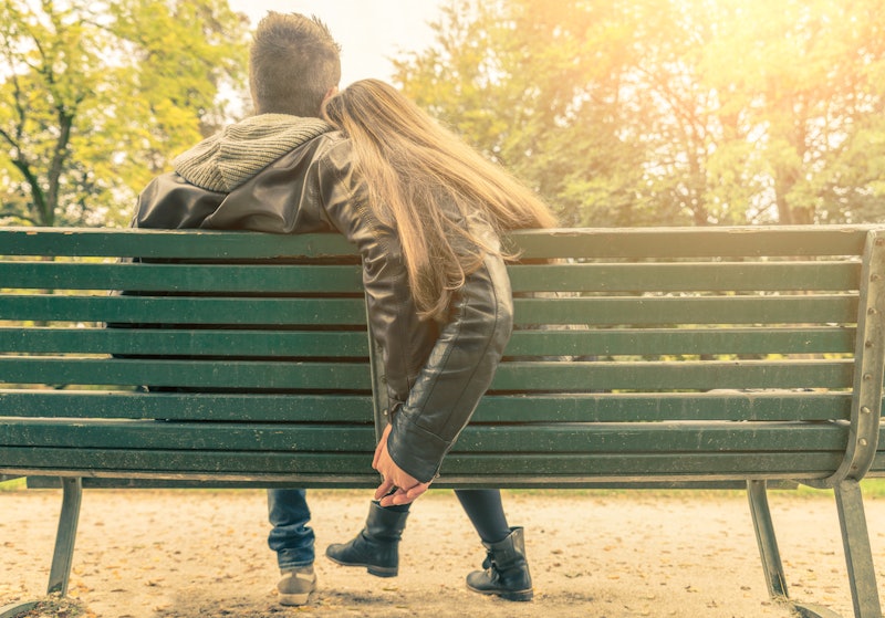 Couple on a bench - Two lovers sitting on a bench in a park and holding themselves by hands - Concep...