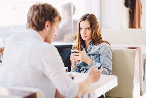 Young man talking on phone ignoring angry mad millennial girlfriend