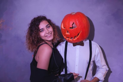 Unusual couple at the Halloween party. Man with carved pumpkin on his head and funny woman near pump...