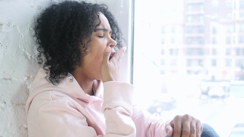 Young African Woman Yawning, Sitting at Window