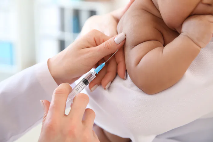 Pediatrician giving little baby an injection in clinic