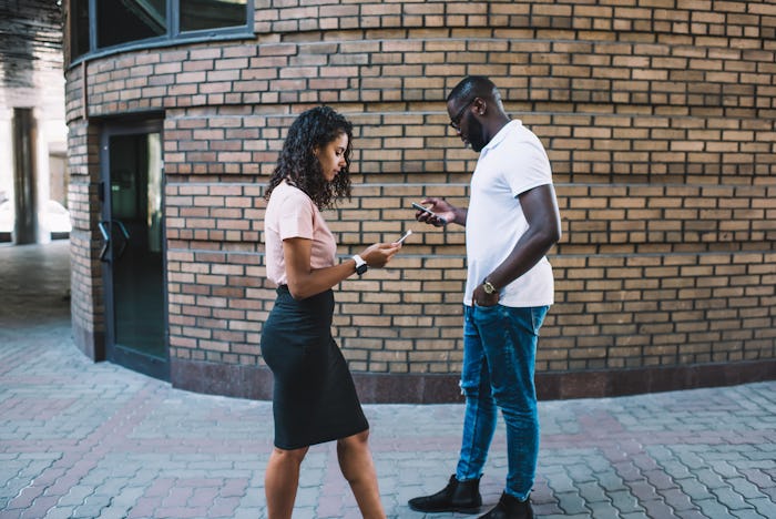 Young woman and man walking with smartphones outdoors ignore real communication prefere online chatt...