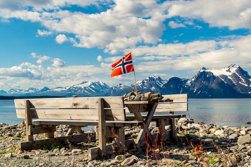 Picnic site rest stop area wooden table decoration and norwegian flag on lake fjord shore. Holidays ...